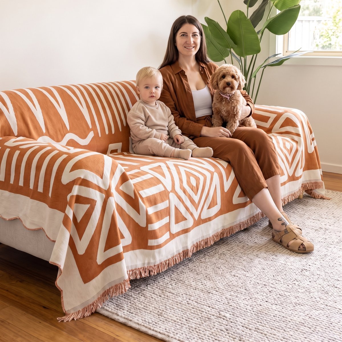 Family and dog on a couch protected by a CouchCare cover with a scalloped edge